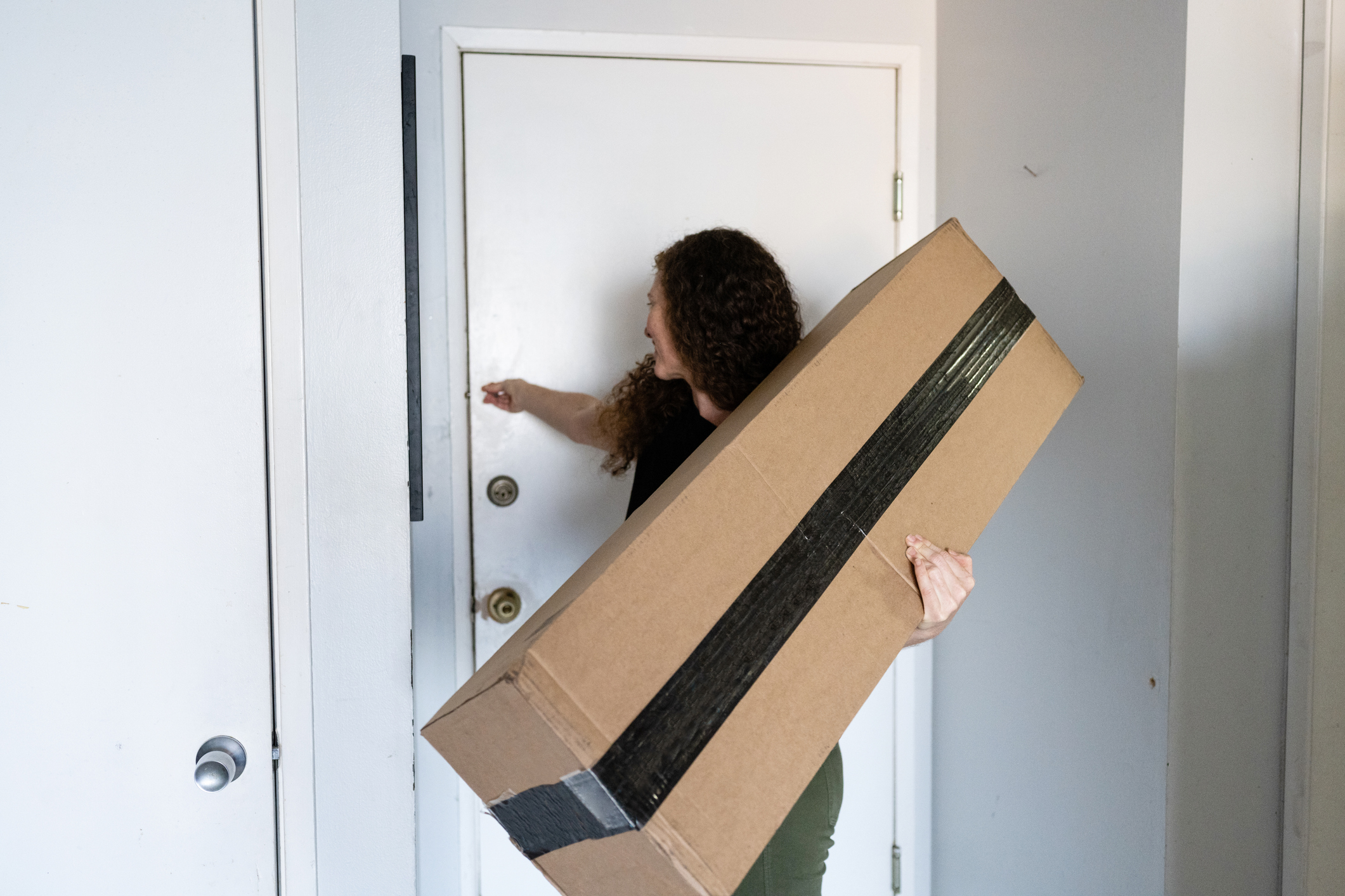 Woman holding a box while closing a door